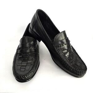 May include: A pair of black leather loafers with a woven design on the front. The loafers have a pointed toe and a low heel.
