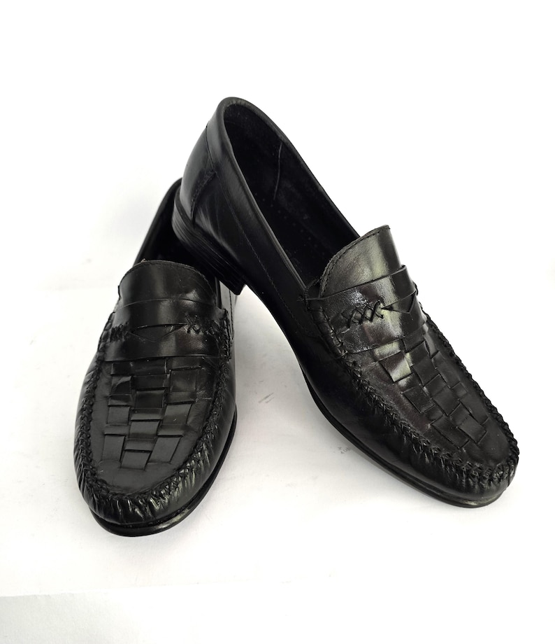 May include: A pair of black leather loafers with a woven design on the front. The loafers have a pointed toe and a low heel.
