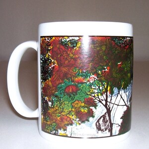 May include: White ceramic mug with a colorful autumn leaf design. The design features red, orange, yellow, and green leaves on a brown branch. The mug has a black rim and handle. The text "Wondermugs" is printed on the bottom of the mug.