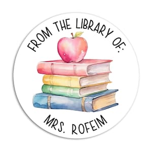May include: A round sticker with the text "From the Library of: Mrs. Roffeim" in black text. A stack of colorful books with a red apple on top.