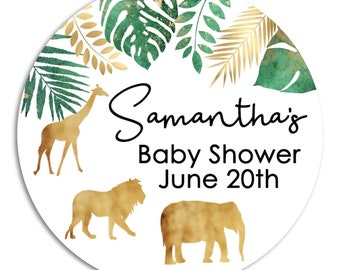 May include: A white round sticker with a green and gold tropical leaf design. The text "Samantha's Baby Shower June 20th" is in black text. There are gold silhouettes of a giraffe, lion, and elephant.