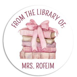 May include: A round sticker with the text "From the Library of: MRS. ROFEIM" in maroon lettering. A stack of books with a pink ribbon bow is in the center of the sticker.