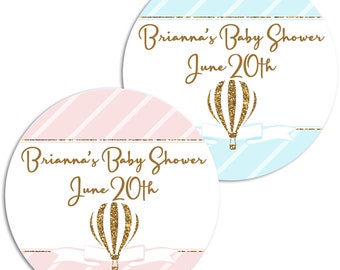 May include: Two round pink and blue baby shower stickers with gold glitter hot air balloons and the text "Brianna's Baby Shower June 20th"