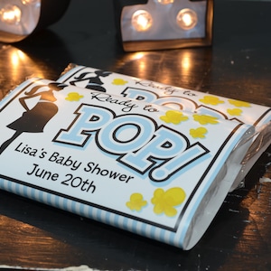 May include: Blue and white favor boxes with the text "Ready to POP!" and "Lisa's Baby Shower June 20th".