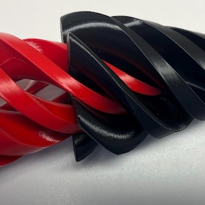 以下が含まれることがあります： 赤と黒の3Dプリントされたらせん状のデザイン。らせんは、互いに噛み合っている2つの別々の部分で構成されています。
