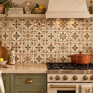Può includere: Un paraschizzi da cucina composto da piastrelle in ceramica quadrate con un motivo ripetitivo floreale e geometrico nei toni del verde salvia, terracotta e crema. Le piastrelle sono disposte a griglia dietro un fornello bianco.