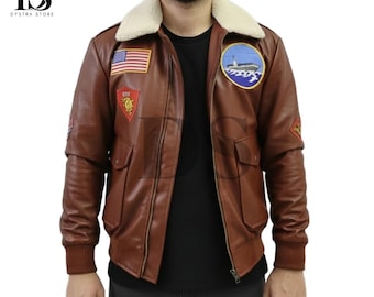 Puede incluir: Chaqueta de cuero marrón con cuello de borreguillo color crema. La chaqueta presenta varios parches, incluyendo una bandera americana y un emblema náutico. Tiene dos bolsillos delanteros y puños acanalados. Chaqueta de estilo bombardero clásico.