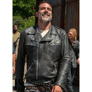 May include: Black leather motorcycle jacket with a notched collar, asymmetrical zipper closure, and multiple zippered pockets. The jacket features a belt at the waist and is worn by a person smiling outdoors.