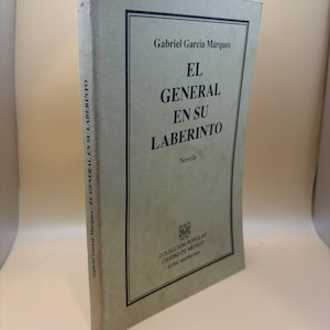 May include: A hardcover book titled "EL GENERAL EN SU LABERINTO" by Gabriel García Márquez. The book has a light gray cover with black text. The title is in large, bold letters. The book is part of the "COLECCION POPULAR CIUDAD DE MEXICO" series.