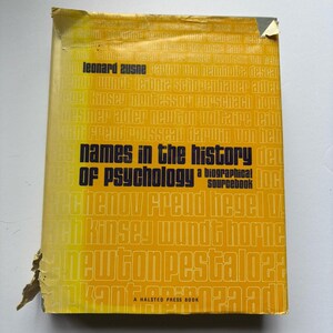 Puede incluir: Un libro amarillo titulado "Names in the History of Psychology" con texto negro. La portada del libro presenta una lista de nombres y el texto "A Halsted Press Book". La portada está desgastada.