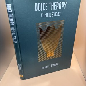 May include: A hardcover book titled "VOICE THERAPY CLINICAL STUDIES" by Joseph C. Stemple. The cover is dark teal with gold foil accents, including a stylized anatomical illustration. The spine also features the title.