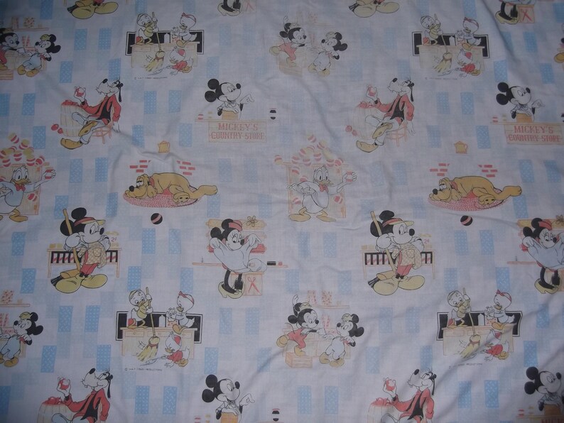 Pu&ograve; includere: Un tessuto azzurro con un motivo ripetuto di personaggi Disney, tra cui Topolino, Minni, Paperino, Pippo e Pluto. La stampa raffigura scene del Mickey's Country Store con vari personaggi che interagiscono in una delicata palette di colori.