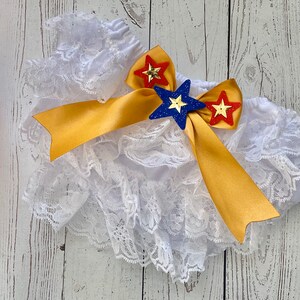 May include: White lace ruffle bloomers with a gold satin bow and red, blue, and yellow star embellishments.
