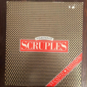 May include: A Question of  Scruples board game box with a black and gold checkered pattern. The title "A Question of Scruples" is in red text. The box also says "Second Edition" and "Over 250 New Dilemmas" in red text.