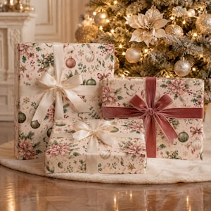 May include: Three rectangular gift boxes wrapped in cream-colored paper featuring a pattern of poinsettias, green foliage, and gold ornaments. The boxes are tied with satin and velvet ribbons in shades of cream and dusty rose.