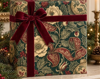May include: A square gift box wrapped in dark green paper featuring a botanical pattern of cream-colored flowers, holly leaves, red berries, and gold ribbons, tied with a wide, deep burgundy velvet ribbon and a large bow on the front.