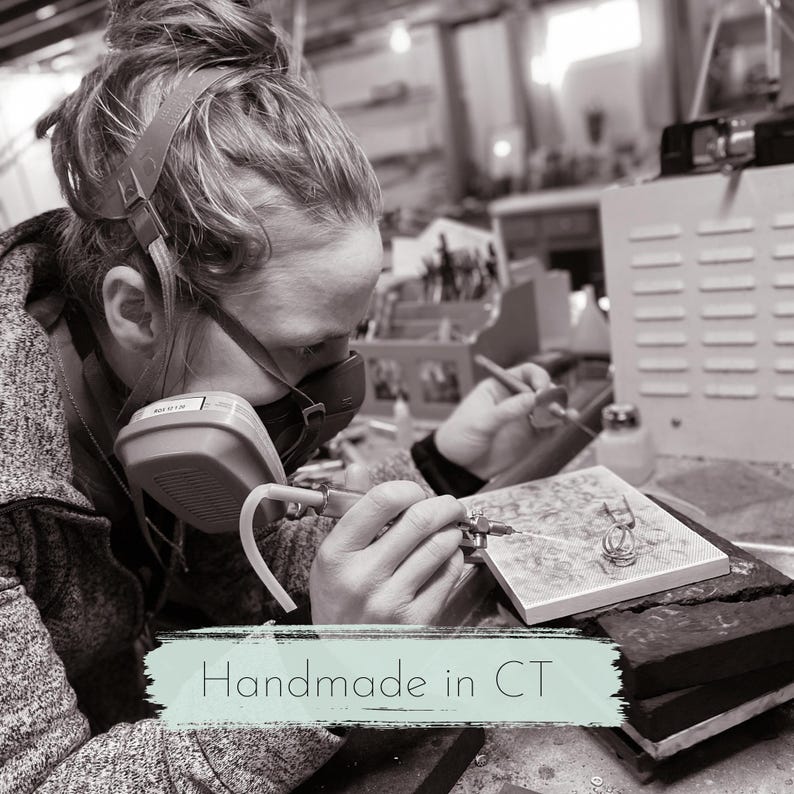 Handmade sterling silver jewelry handcrafted in Connecticut by a small business.  This image shows a woman using a torch to solder silver jewelry in a home studio.