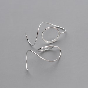 side view of a pair of modern, minimalist threader earrings that showcase a simple lightweight circle and unique spiral ear wire