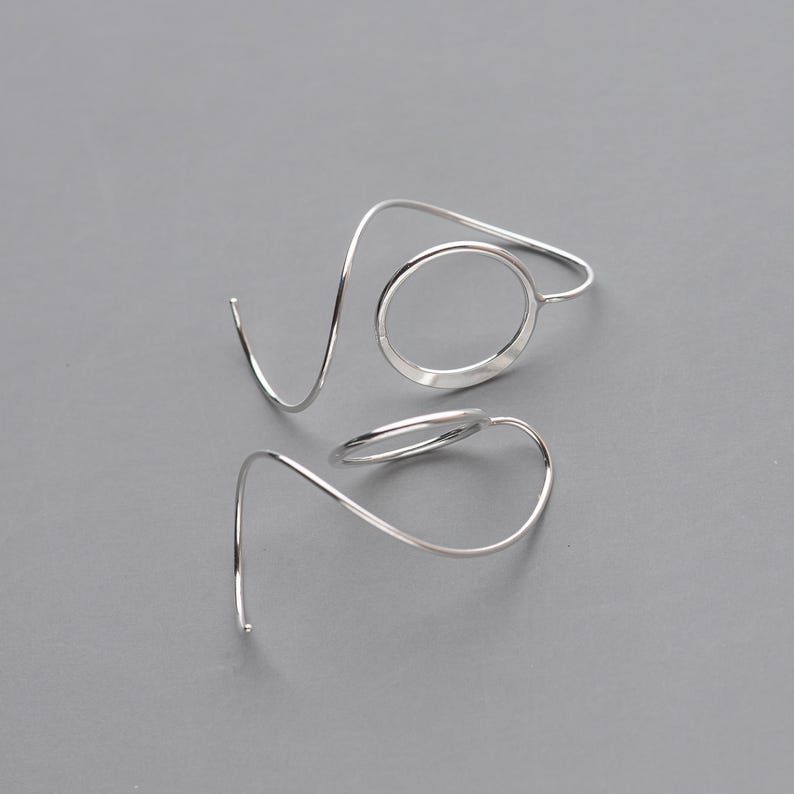 side view of a pair of modern, minimalist threader earrings that showcase a simple lightweight circle and unique spiral ear wire