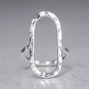May include: A silver ring with a hammered oval design. The ring is open and has a textured finish.