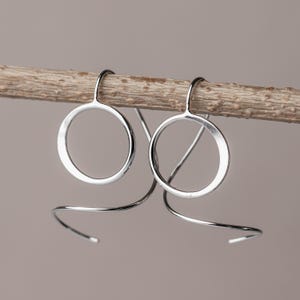 sterling silver spiral threader earrings hanging from a stick to show off their dimensional sculptural design