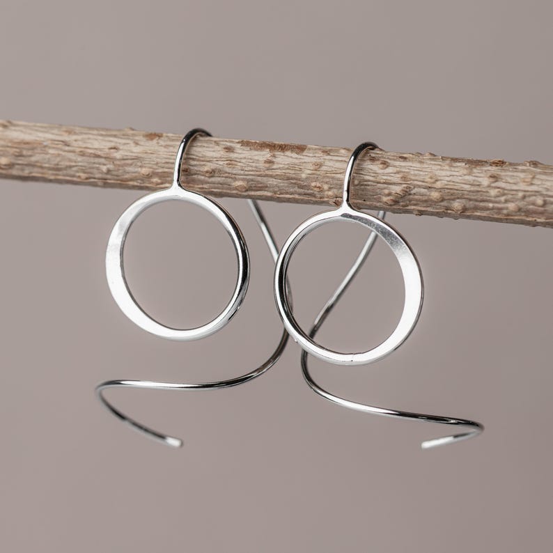 sterling silver spiral threader earrings hanging from a stick to show off their dimensional sculptural design