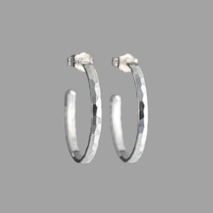 May include: A pair of silver hoop earrings with a hammered texture.