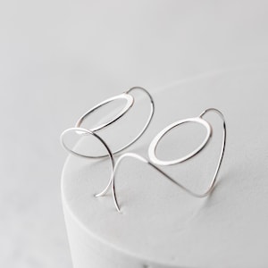 sculptural sterling silver threader earrings are shown from a side angle so you can see the spiral ear wires and how they connect to the hammered sterling silver circles.