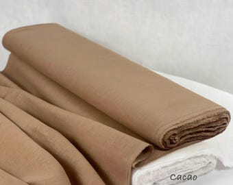 Op de afbeelding: Een rol stof in cacaokleur met een zichtbare geweven textuur. Het textiel is gedrapeerd om de valling en het gewicht te tonen. De tekst in de rechterbenedenhoek luidt: Cacao 100% Linen Fabric. Het materiaal heeft een matte afwerking.