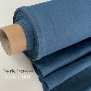 May include: A roll of dark denim blue 100% linen fabric. The textile features a visible woven texture and is wrapped around a cylindrical cardboard core. The text "Dark Denim 100% LINEN" is printed on the left side of the image.
