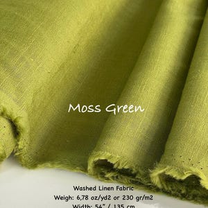 May include: A bolt of moss green washed linen fabric with a visible weave texture. The text on the fabric reads Moss Green, Washed Linen Fabric, Weigh: 6.78 oz/yd2, and Width: 54 inches. The fabric has frayed edges and is folded in layers.