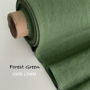 May include: A roll of forest green fabric made of 100% linen. The textile features a visible woven texture and is wrapped around a cardboard core. The text Forest Green 100% LINEN is printed on the left side of the image in a simple font.