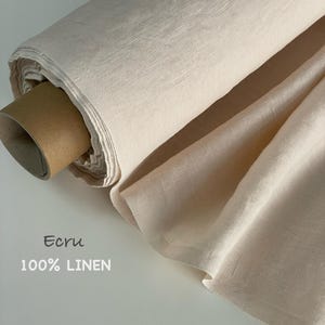 Peut inclure: Un rouleau de tissu 100% lin de couleur écru enroulé autour d'un tube en carton brun. Le textile présente une texture tissée visible et une teinte beige clair. Le texte Ecru 100% LINEN est imprimé en bas à gauche de l'image.