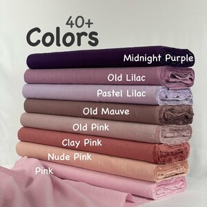 May include: A stack of fabric bolts in various shades of purple, mauve, and pink, labeled with text including Midnight Purple, Old Lilac, Pastel Lilac, Old Mauve, Old Pink, Clay Pink, Nude Pink, and Pink, with the header text 40+ Colors.