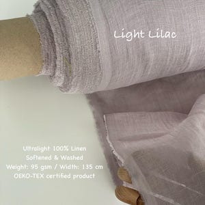 May include: A roll of light lilac-colored linen fabric. The text "Light Lilac" is visible. The fabric is ultralight, 100% linen, softened, and washed. The width is 135 cm. The fabric is an OEKO-TEX certified product.