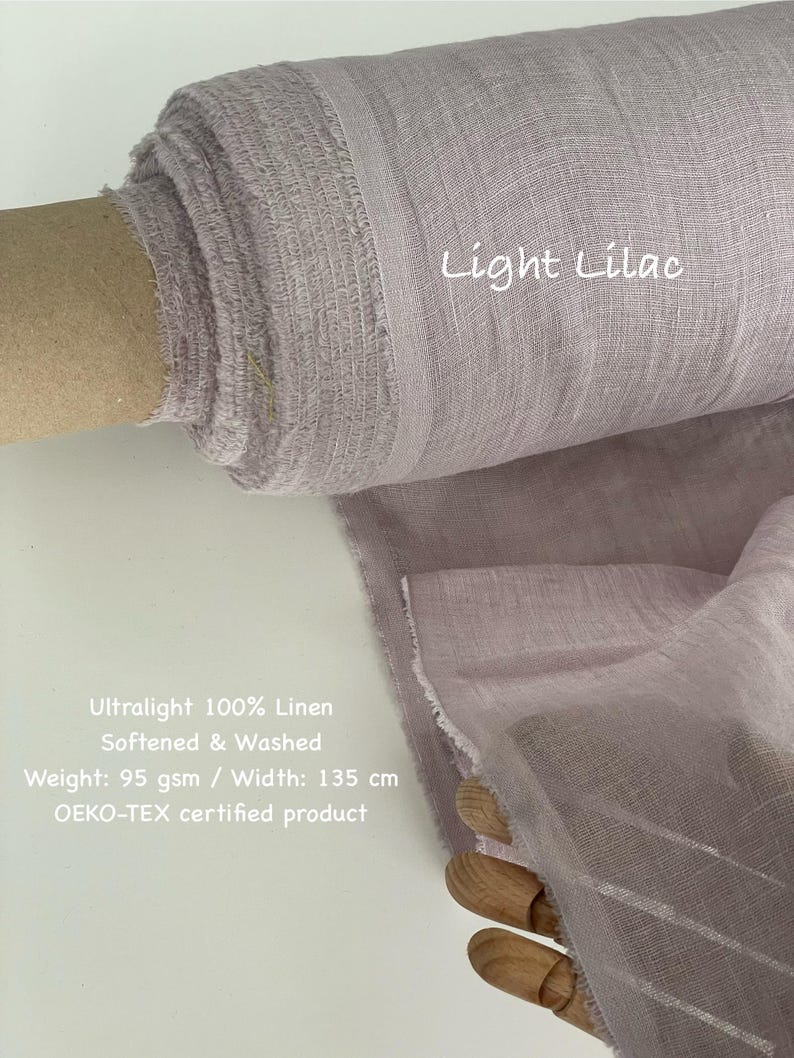 May include: A roll of light lilac-colored linen fabric. The text "Light Lilac" is visible. The fabric is ultralight, 100% linen, softened, and washed. The width is 135 cm. The fabric is an OEKO-TEX certified product.