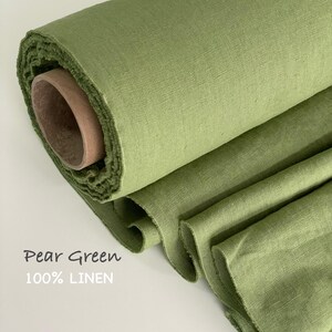 May include: A roll of pear green 100% linen fabric with a visible woven texture. The fabric is wrapped around a cylindrical cardboard core, with several layers of the green textile cascading downward. The text Pear Green 100% LINEN is visible.