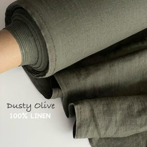 Può includere: Un rotolo di tessuto color oliva polveroso con una trama visibile. Il testo Dusty Olive 100% LINEN è stampato sul lato sinistro. Il tessuto è parzialmente srotolato, mostrando pieghe e la trama densa e naturale del materiale in lino.