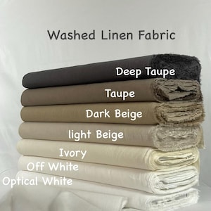 Könnte beinhalten: Ein Stapel aus sieben Rollen gewaschenem Leinenstoff in verschiedenen neutralen Farbtönen. Die von oben nach unten beschrifteten Farben sind Deep Taupe, Taupe, Dark Beige, light Beige, Ivory, Off White und Optical White. Der Stoff hat sichtbare Fransen.