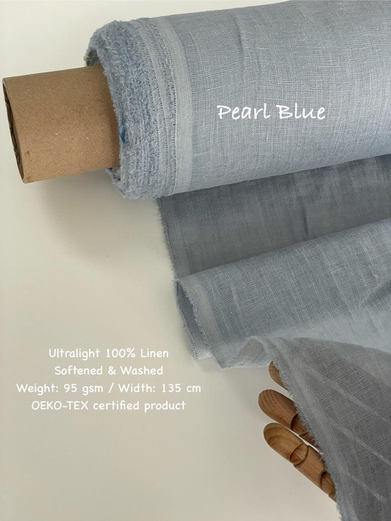 May include: A roll of pearl blue ultralight 100% linen fabric. The fabric is softened, washed, and weighs 95 gsm. The width of the fabric is 135 cm. The text "Pearl Blue" is visible on the fabric. The product is OEKO-TEX certified.