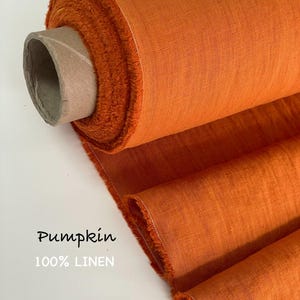 May include: A roll of vibrant orange fabric with a visible woven texture, featuring a frayed edge and a cardboard core. The text "Pumpkin" and "100% LINEN" is printed on the left side of the image, indicating the color and material composition.
