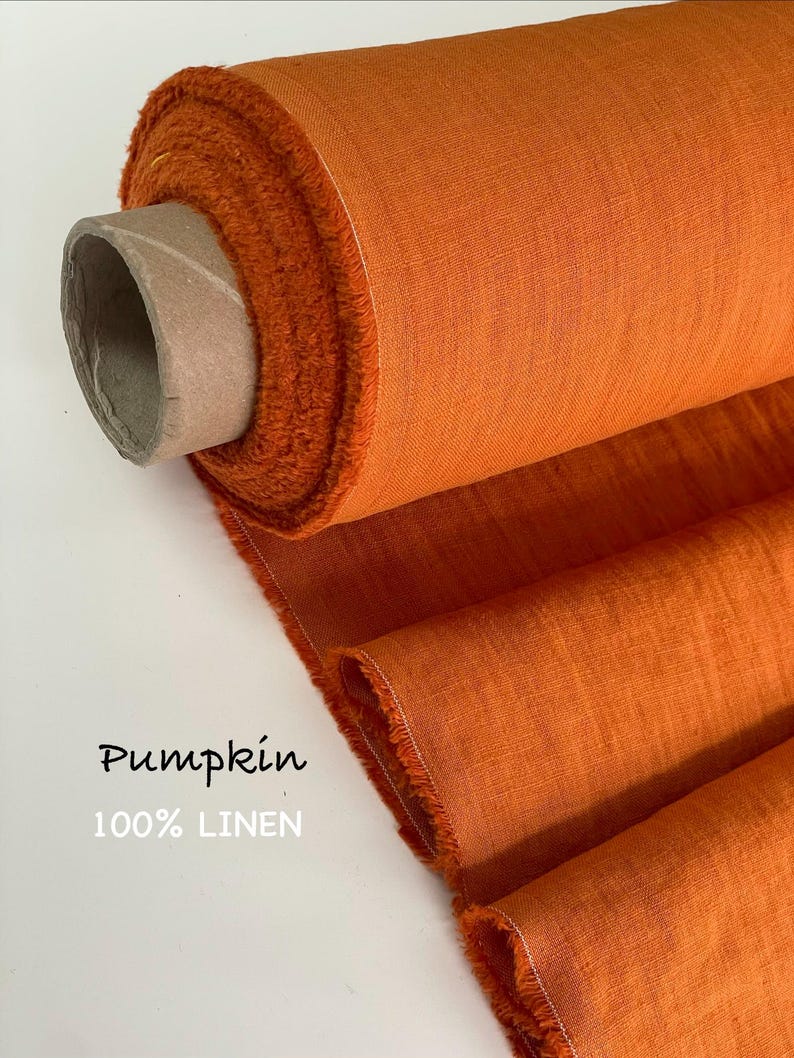 May include: A roll of vibrant orange fabric with a visible woven texture, featuring a frayed edge and a cardboard core. The text "Pumpkin" and "100% LINEN" is printed on the left side of the image, indicating the color and material composition.