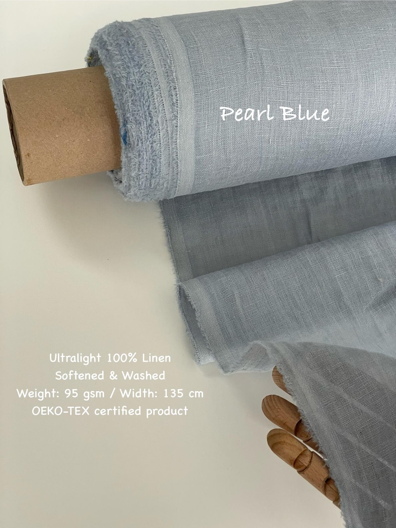 May include: A roll of pearl blue ultralight 100% linen fabric. The fabric is softened and washed, with a weight of 95 gsm and a width of 135 cm. The text "Pearl Blue" is visible on the fabric. The fabric is an OEKO-TEX certified product.