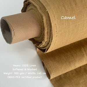 May include: A roll of camel-colored heavy 100% linen fabric. The fabric is softened and washed, with a weight of 300 gsm and a width of 145 cm. The text "Camel" is visible on the fabric. The product is OEKO-TEX certified.