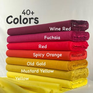 May include: A stack of seven fabric bolts in a gradient of warm colors, including wine red, fuchsia, red, spicy orange, old gold, mustard yellow, and yellow. The text 40+ Colors is printed at the top, with labels identifying each fabric color.