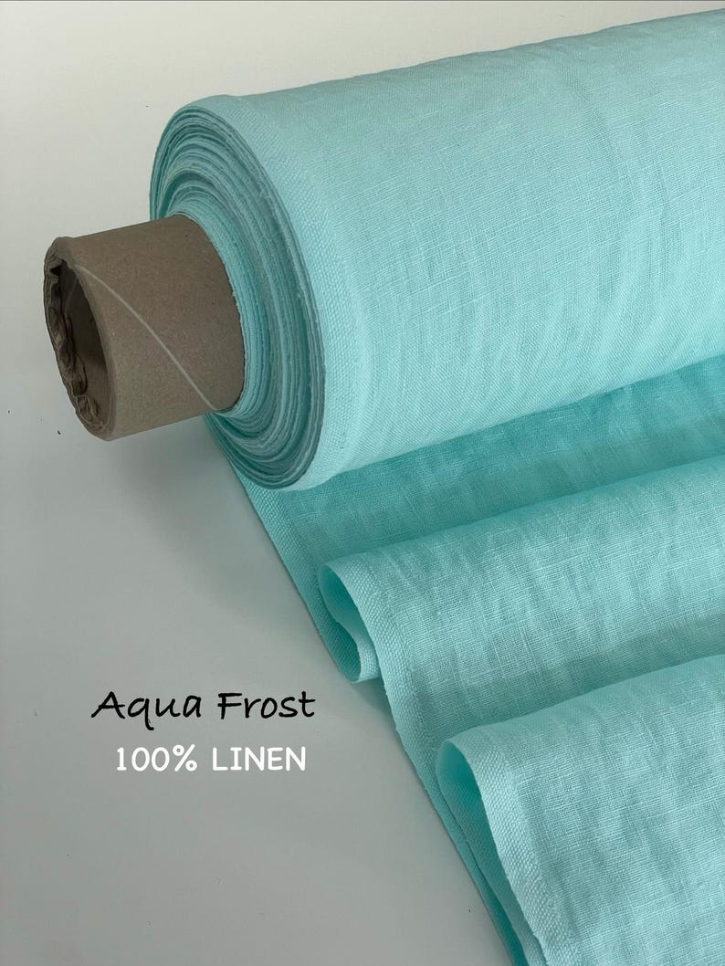 May include: A bolt of aqua frost colored fabric made of 100% linen. The textile is wrapped around a cardboard core, showing a visible woven texture and a light turquoise hue. The text Aqua Frost 100% LINEN is printed on the lower left side.