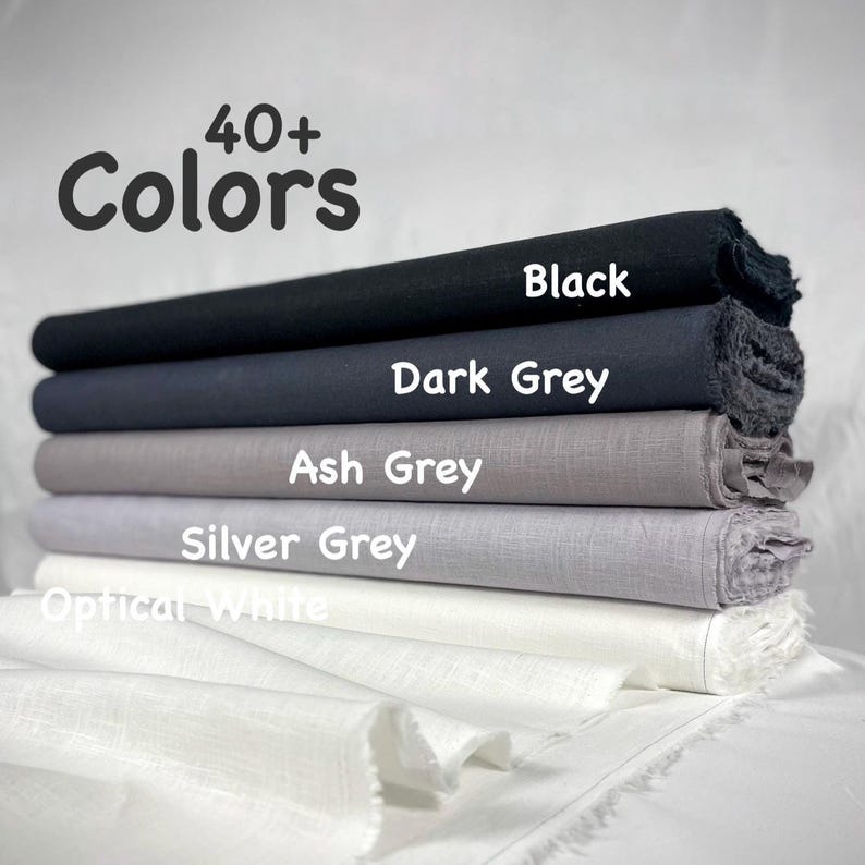 May include: A stack of five fabric bolts in a gradient of shades including black, dark grey, ash grey, silver grey, and optical white. The text 40+ Colors is displayed at the top, with individual labels identifying each fabric color layer.