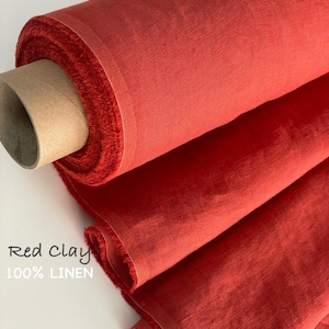 May include: A roll of red clay colored fabric made of 100% linen. The textile features a visible woven texture and frayed edges along the unrolled portion. The text Red Clay 100% LINEN is printed on the lower left side of the image.