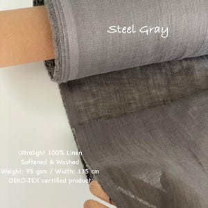May include: A roll of steel gray ultralight 100% linen fabric. The fabric is softened and washed, with a weight of 95 gsm and a width of 135 cm. The text "Steel Gray" is visible on the fabric. The product is OEKO-TEX certified.