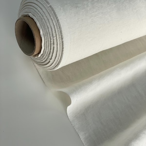 May include: A roll of white linen fabric. The fabric is tightly rolled and has a natural, slightly textured surface.